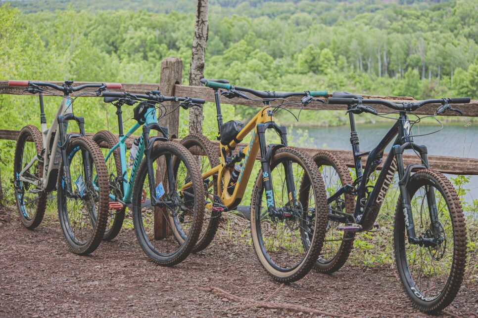 four multicolored mountain bikes parked beside brown wooden railing