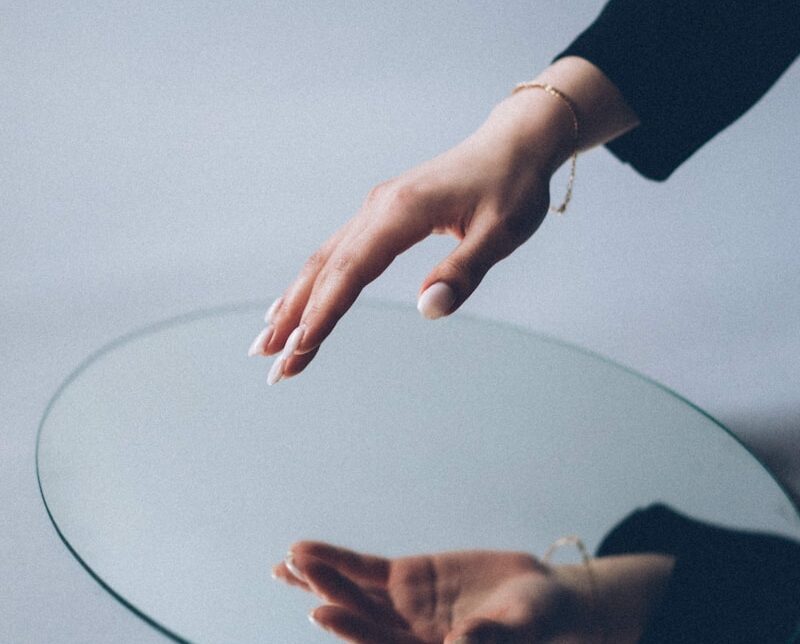 person in black long sleeve shirt holding round glass
