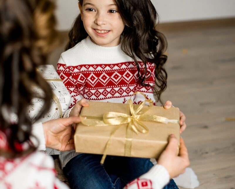 girl in red and white sweater holding brown box