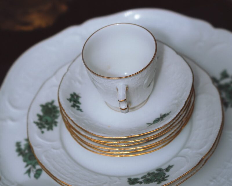 a stack of white and gold china plates