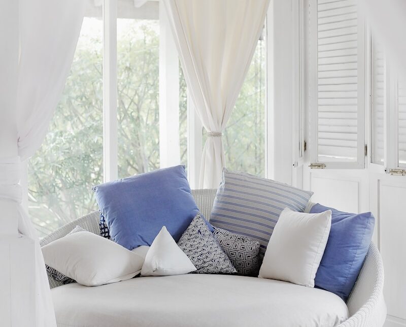 white cuddle chair and throw pillows near window