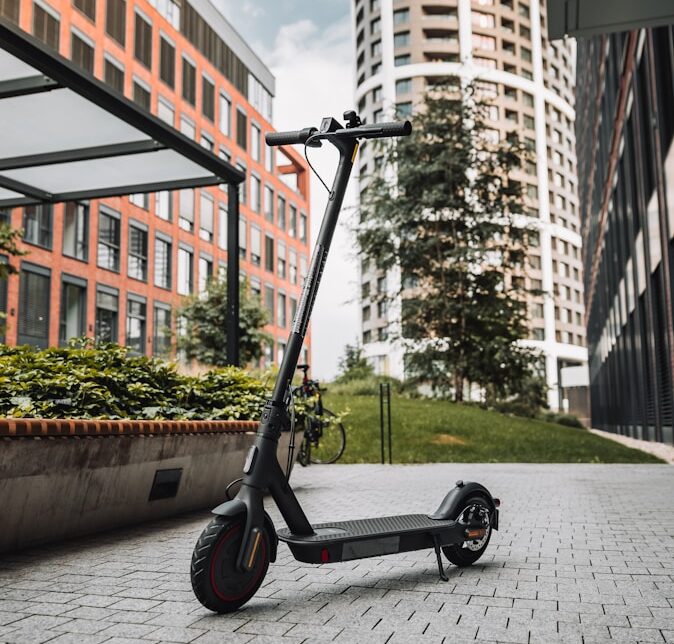 black and gray kick scooter on gray concrete pavement near brown concrete building during daytime