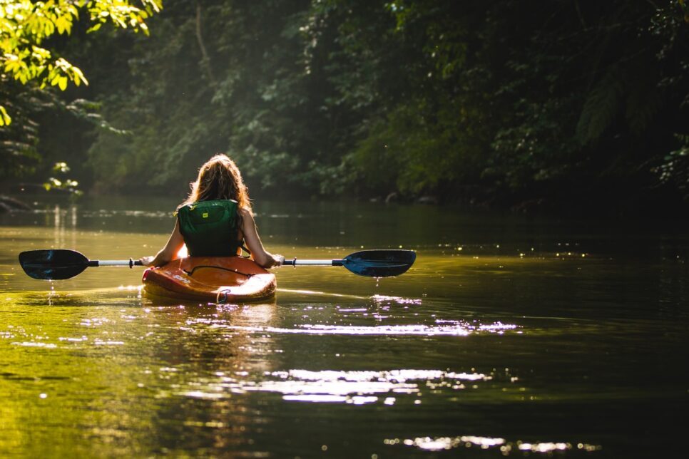 woman on kayak on body of water holding paddle