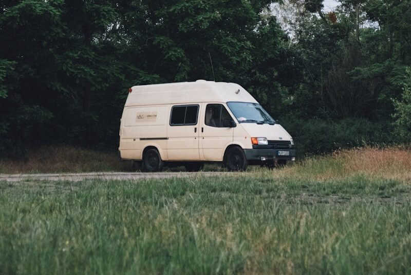 white van parked near green trees during daytime