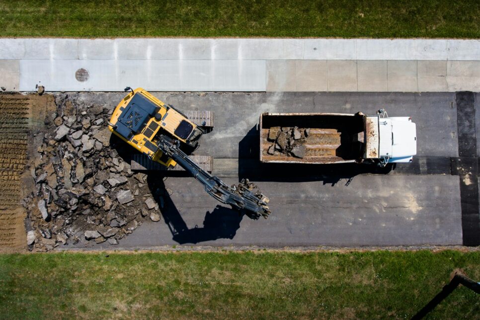 aerial photography of yellow heavy equipment beside white dump truck at daytime