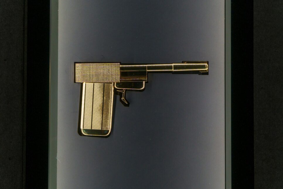 A golden pistol is displayed in a case.